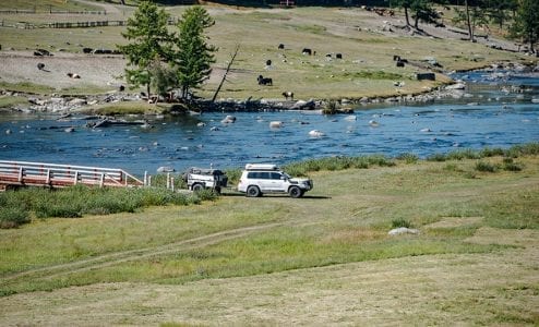 4WD off-road vehicle crossing grassy terrain near river – Torqit adventure scene