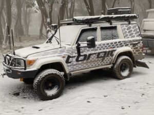 Toyota 76 Series Troop Carrier with Torqit camo wrap driving through snow