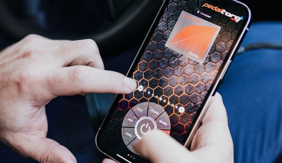 Hands adjusting settings on the Pedal Torq Plus throttle controller app on a smartphone