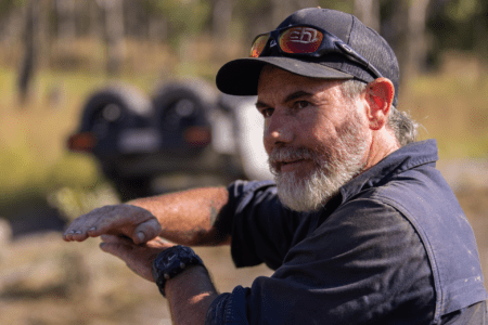 Graham Cahill wearing a cap and sunglasses, sitting outdoors while sharing his top 4WD tracks near Perth.
