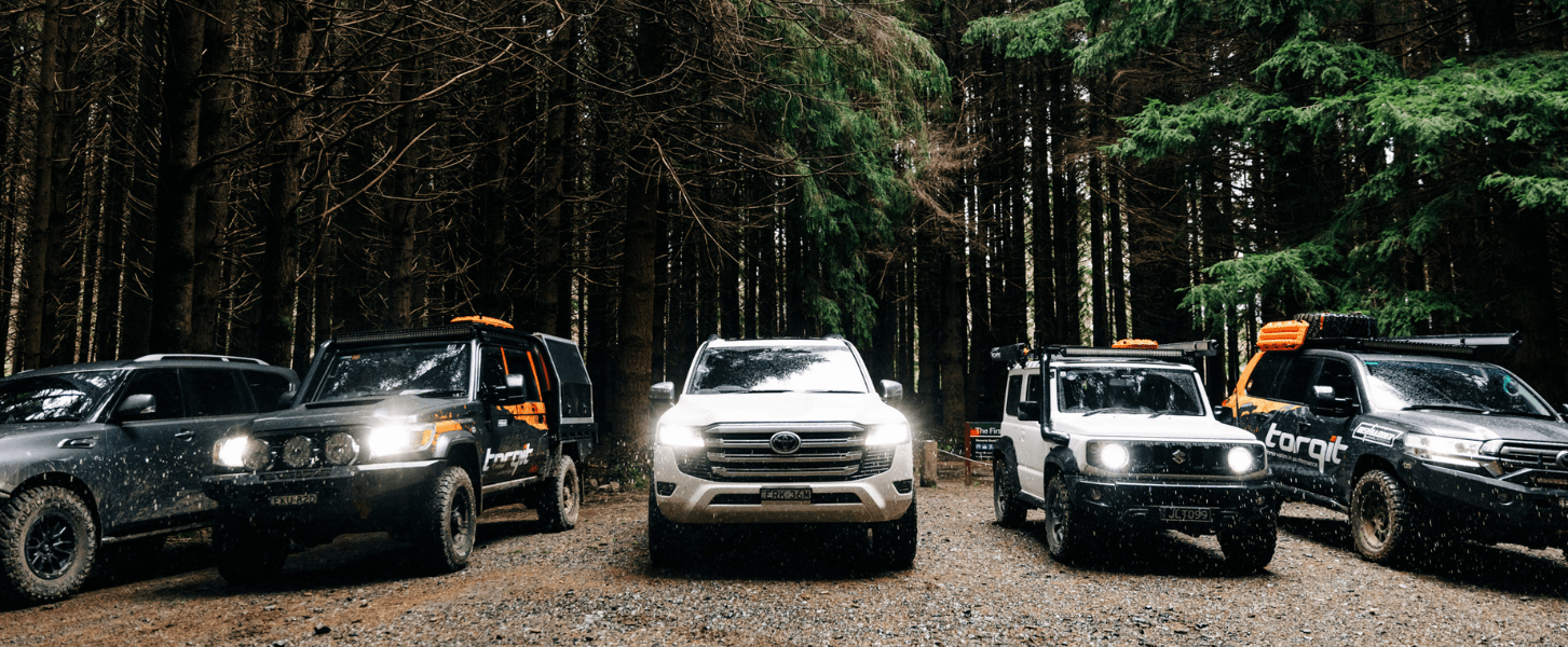 Torqit 4WD vehicles lined up in a forest trail.