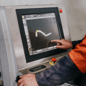 Operator using a mandrel bender control panel for precision exhaust manufacturing.