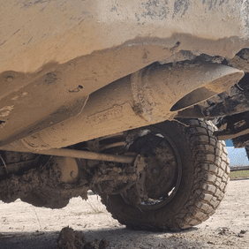 Close-up of Torqit stainless steel exhaust under a 4WD covered in mud