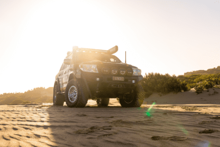 Toyota LandCruiser 200 Series driving on sandy dunes at sunset with off-road upgrades.